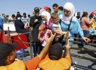 Members of the Turkish coast guards help a Syrian migrant family to disembark on the shore in Cesme, near the Aegean port city of Izmir