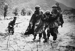 Capt. Emil Kapaunk, right, former chaplain with 1st Cavalry Division, helps another soldier carry an exhausted troop off the battlefield early in the Korean War.